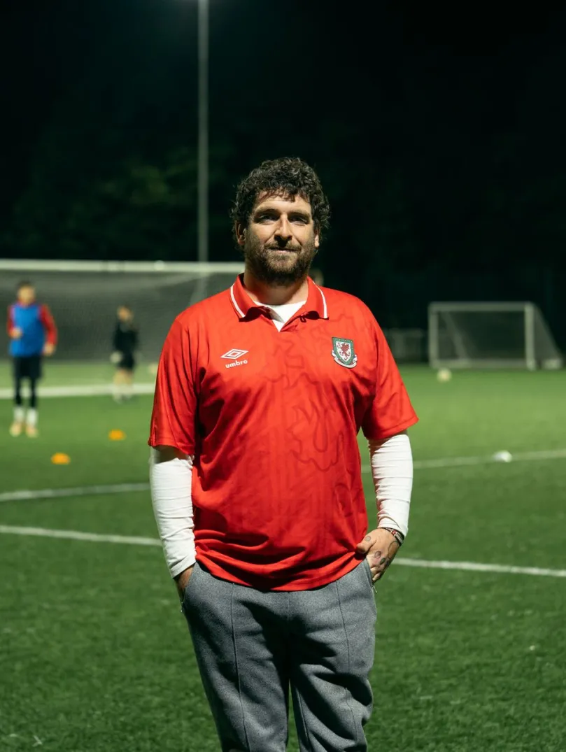 Ein Mann auf einem Fußballfeld während hinter ihm ein Spiel stattfindet.