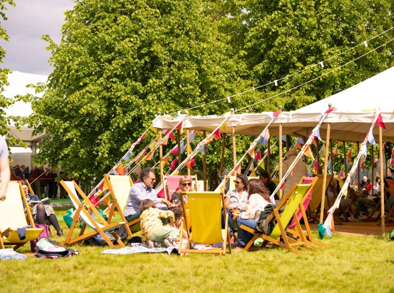 People sat around on chairs outside of a tent at the festival