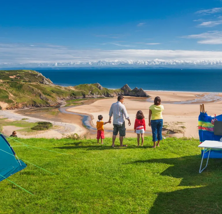 A family of four at a campsite looking over a beach and sea