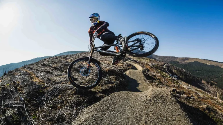 A woman on a mountain bike taking a sharp corner over rocky terrain