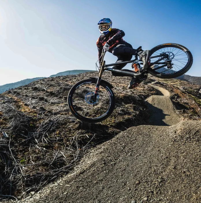 A woman on a mountain bike taking a sharp corner over rocky terrain