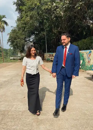 Man in blue suit holding wife's hand in long black skirt