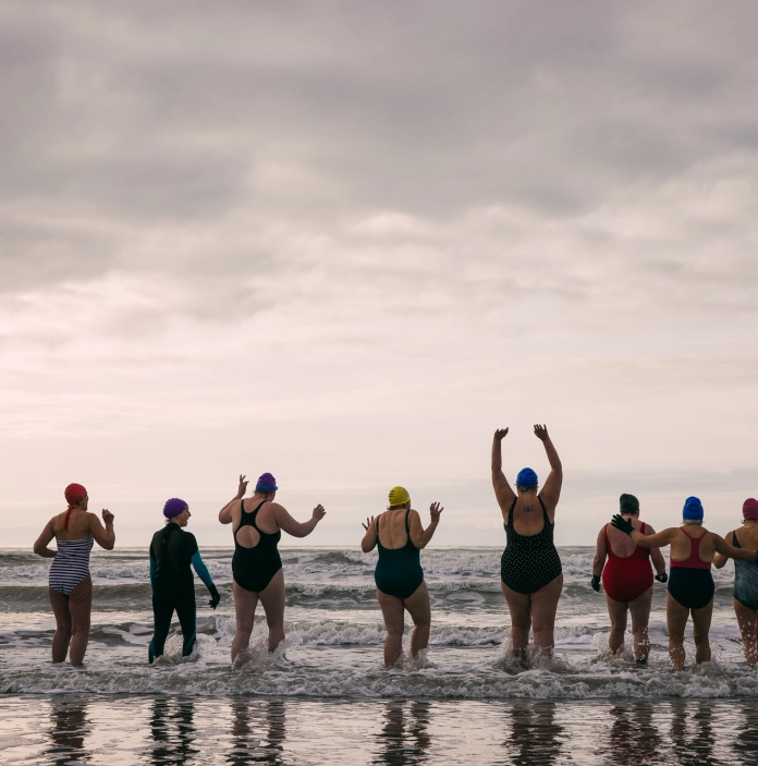 A group of people about to swim in the sea.