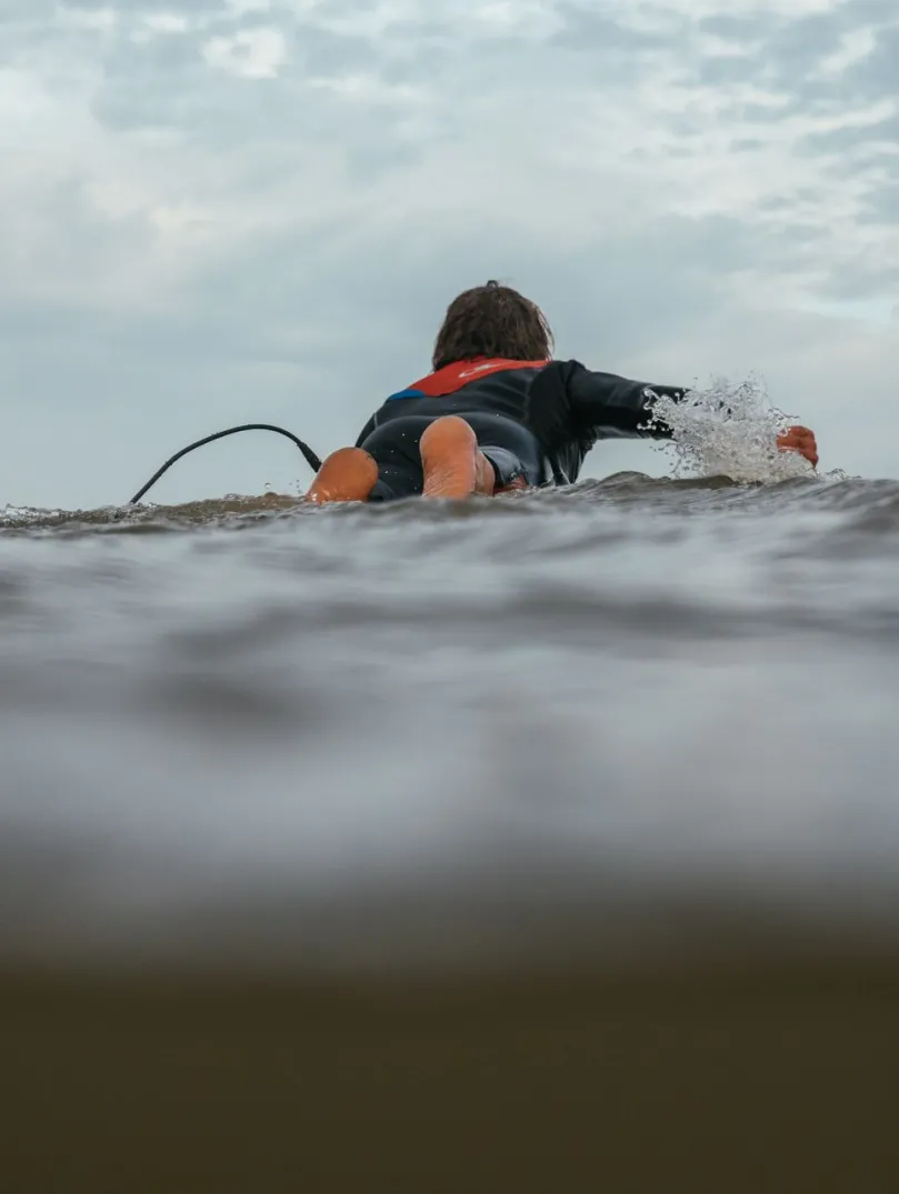 A person lying on a surf board in the sea.