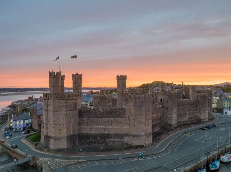 The exterior of the castle with a sun set in background.