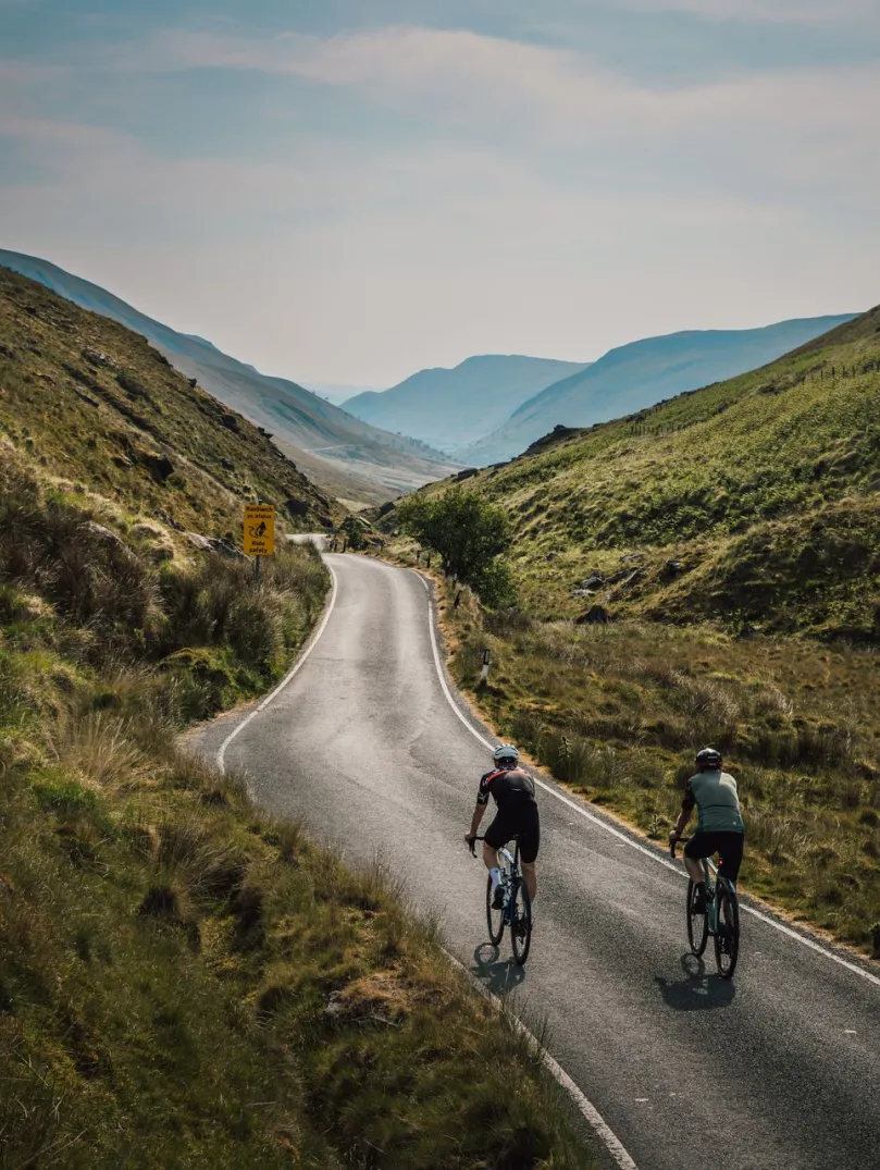 Two people cycling along a mountain road.