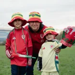 Trois personnes sourient à la caméra en portant des chapeaux seau gallois.