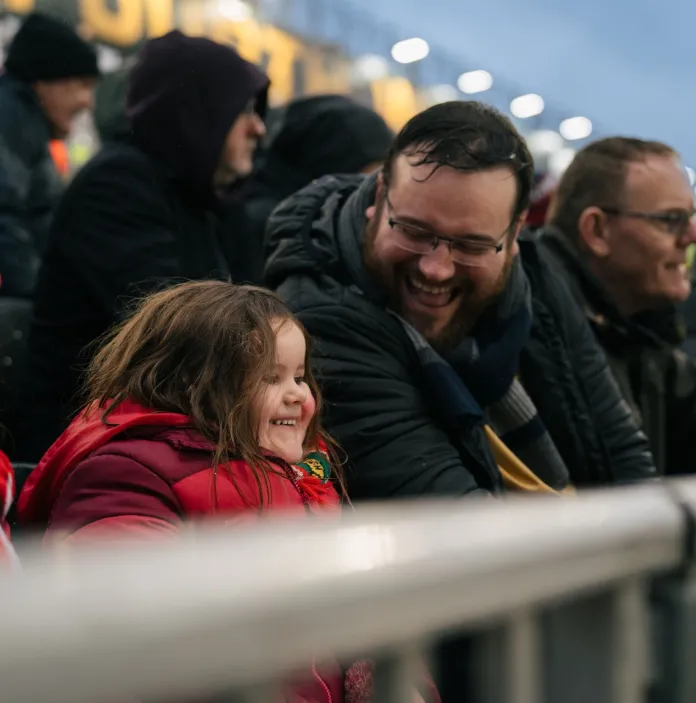 People smiling in the crowd at a football game.