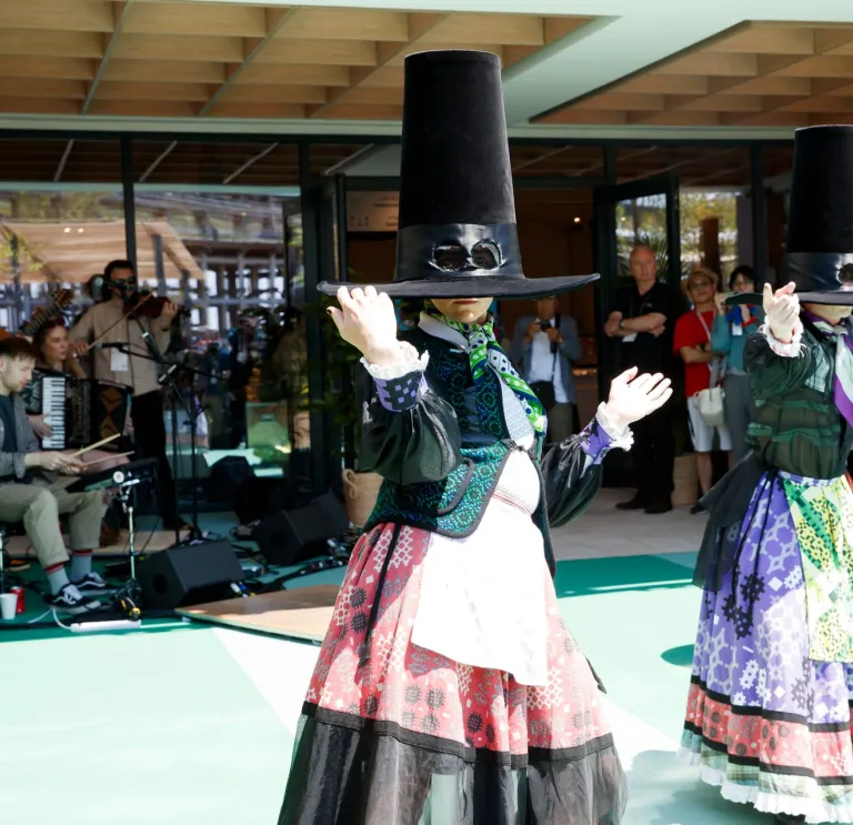 Dancers in traditional Welsh dress with large oversized hats, in mid-performance