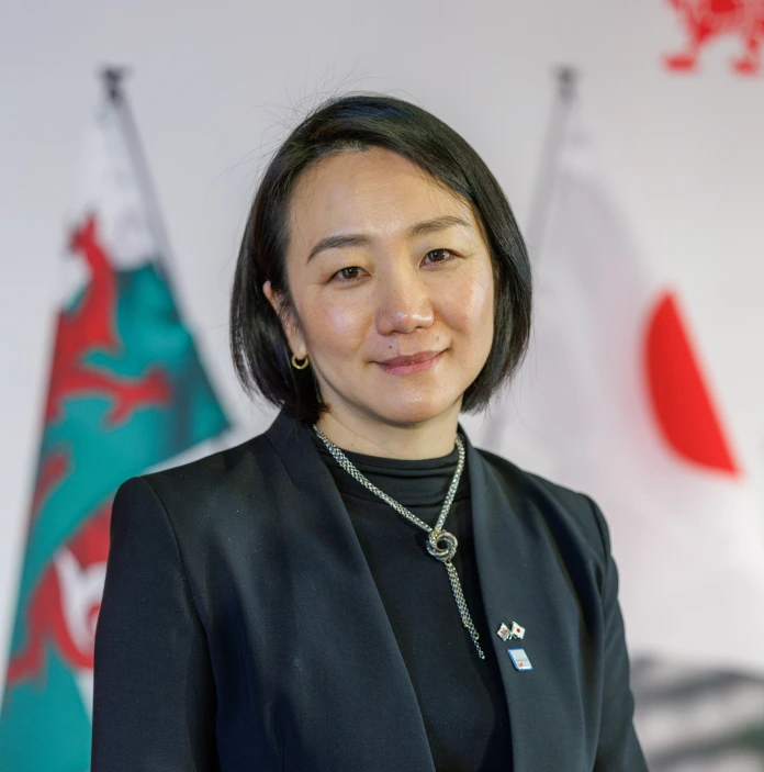 ウェールズと日本の旗が背後にある立って微笑む女性