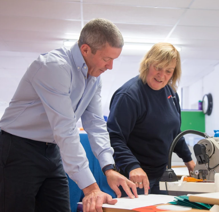 Two people consulting product plans on a table