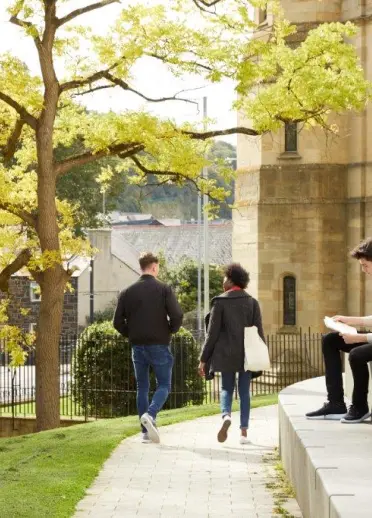 Two people walking and one sat on steps Bangor University 