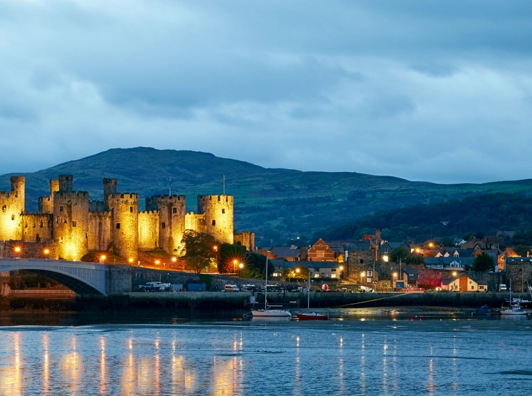 Conwy Castle at dusk lit up with reflection in water