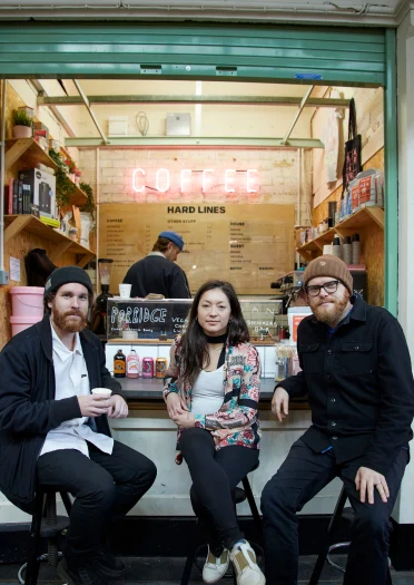 Huw Stephens sitzt mit Freunden vor Hard Lines Coffee