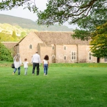 family in field walking towards a stone building.
