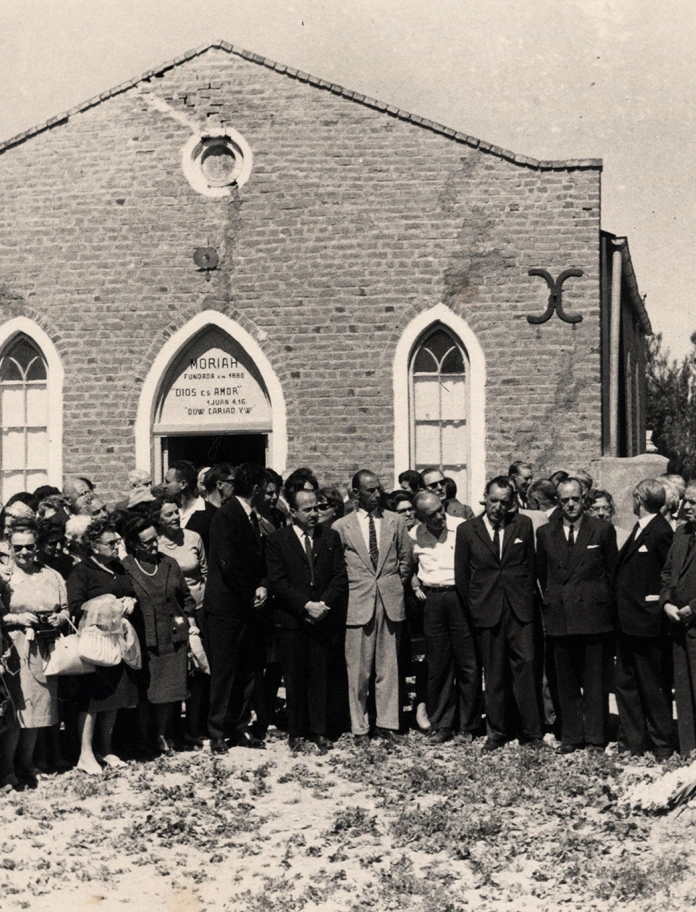 large group of people around memorial outside chapel.