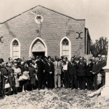 large group of people around memorial outside chapel.