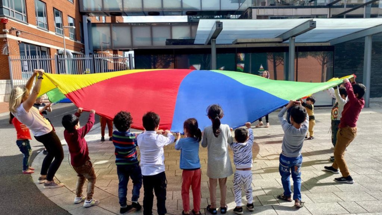 A group of children playing with a parachute.