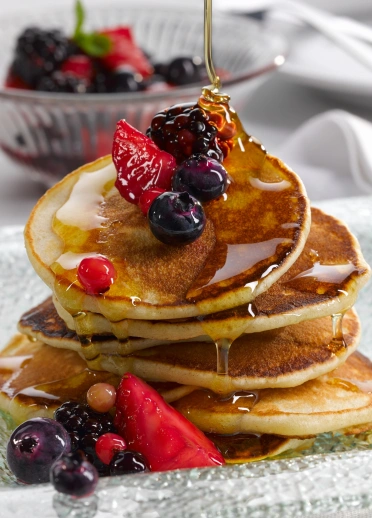 A stack of pancakes with fruit and syrup
