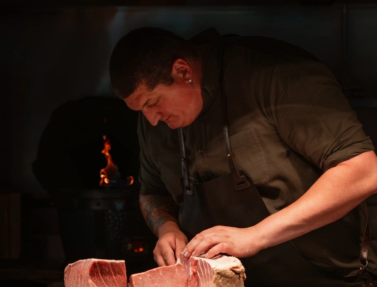A person cutting meat in the kitchen.