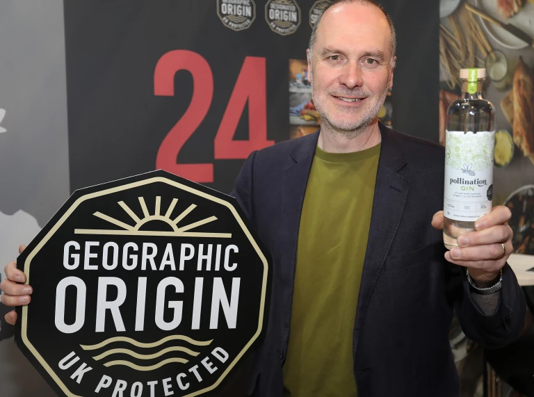 A man smiling at the camera holding a bottle of gin.