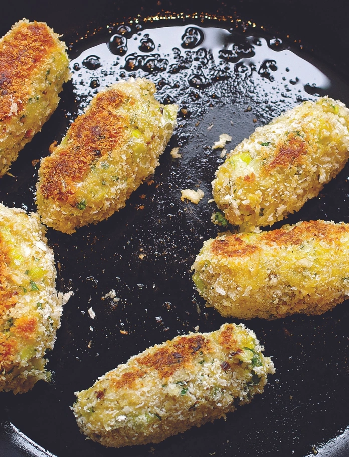 Sechs Glamorgan Sausages, die in einer Pfanne braten.