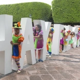 Colourfully dressed people amongst large Hay Festival letters.