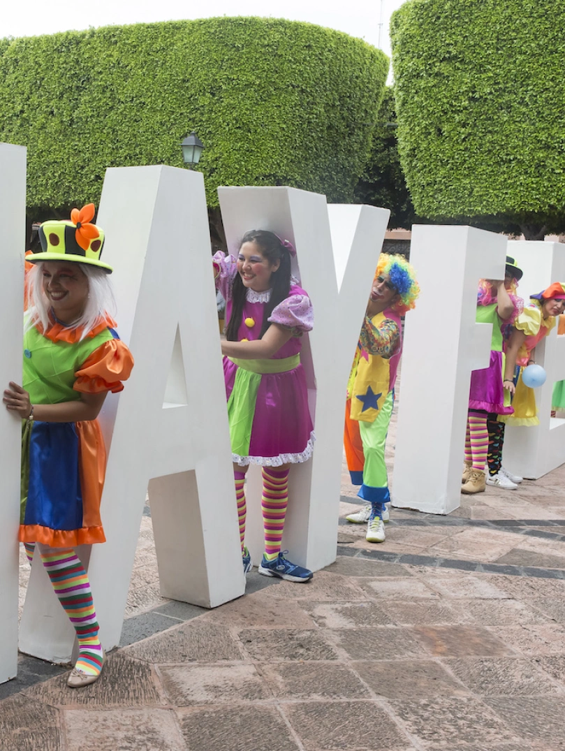 Colourfully dressed people amongst large Hay Festival letters.