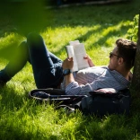 A person lying on the grass reading a book.