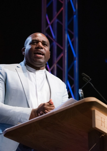 A man stood at a lecturn giving a talk.