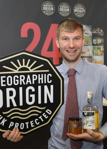 A man holding the honey smiling at the camera.