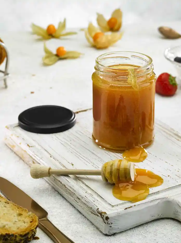 Un tarro de miel con tostadas y frutos rojos.