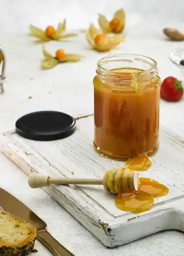 An image of honey in a har surrounded by toast and berries.