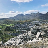 A mountain of slate in the foreground, with terraced houses and further mountains in the background