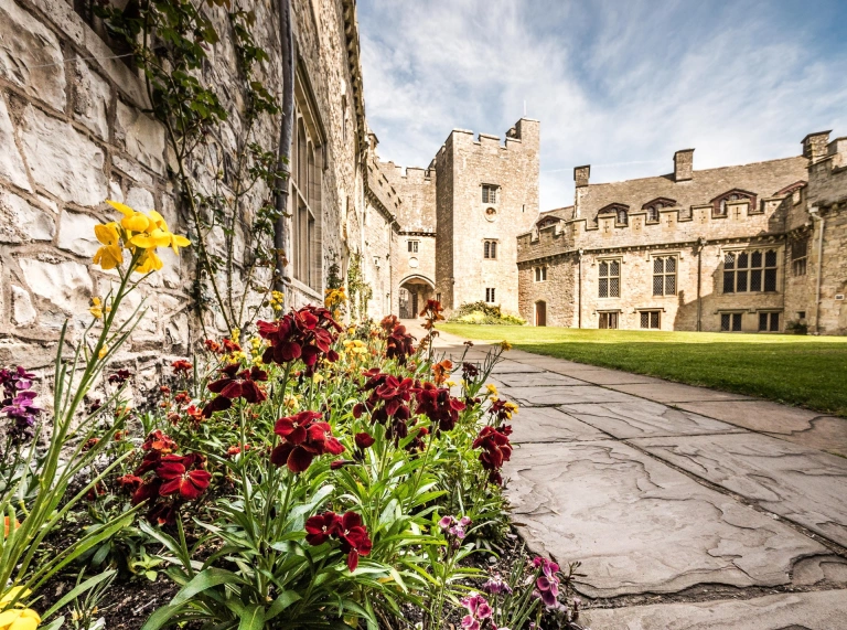 The exterior of the college showing a lawn and flowers.
