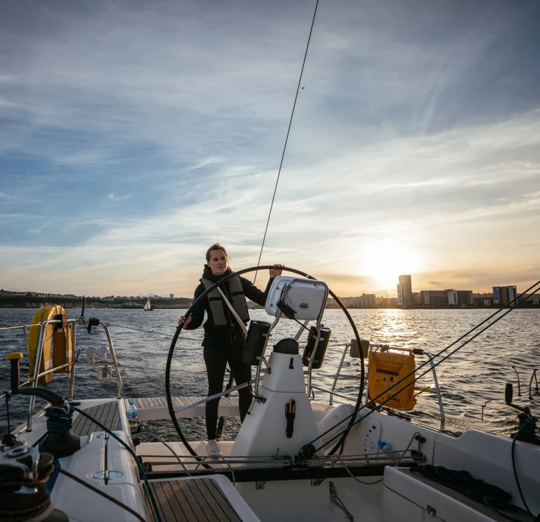 Hannah Mills at the wheel of the yacht, sailing in Cardiff Bay