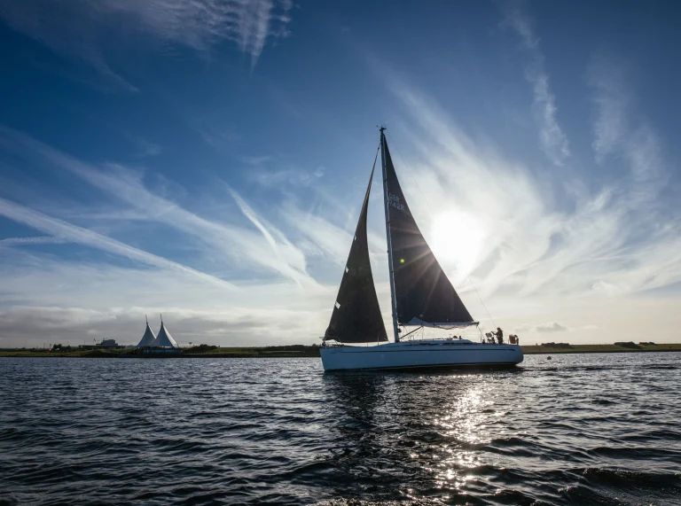 Boat in silhouette sailing along the Barrage on a clear day, blocking the sun