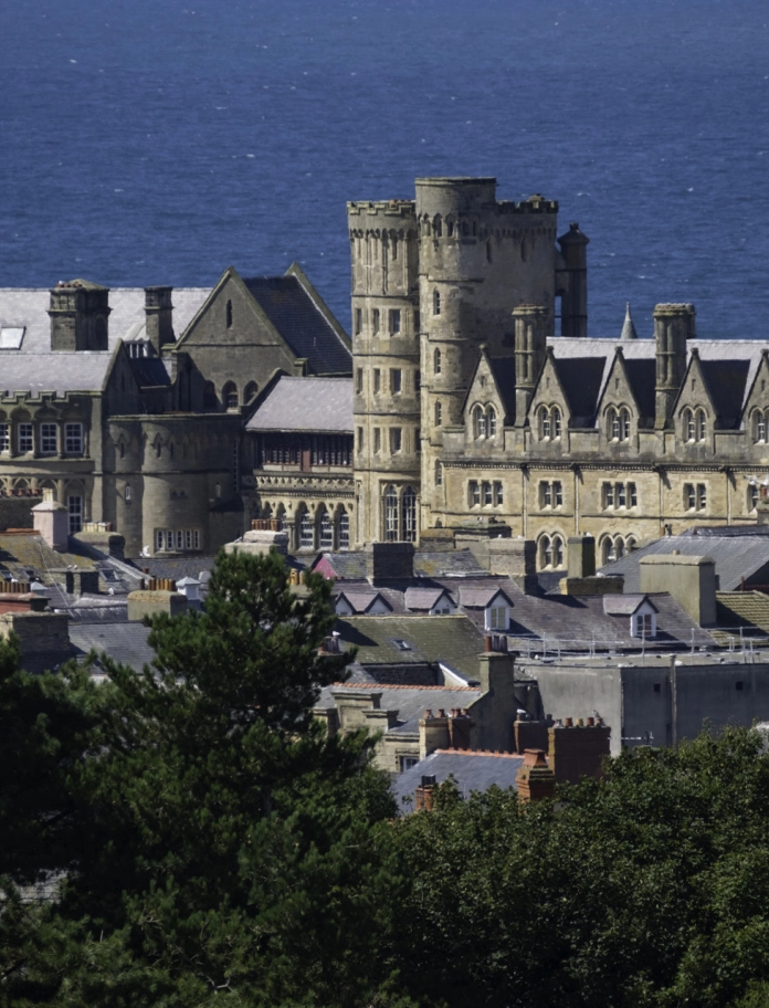 El edificio de estilo gótico del Old College en Aberystwyth con el mar de fondo