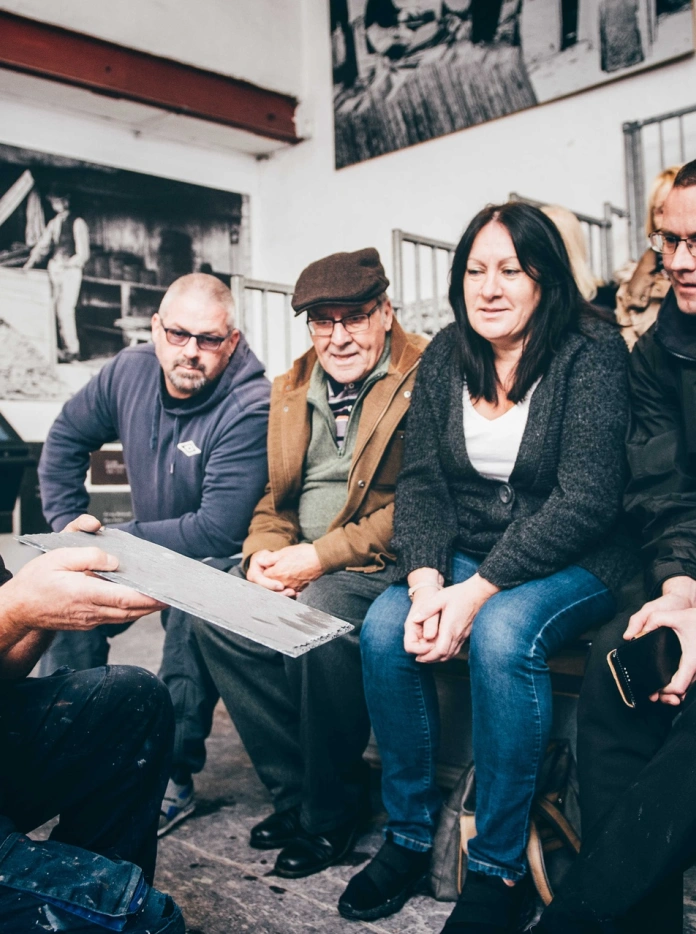 A tour group learning how to split slate.
