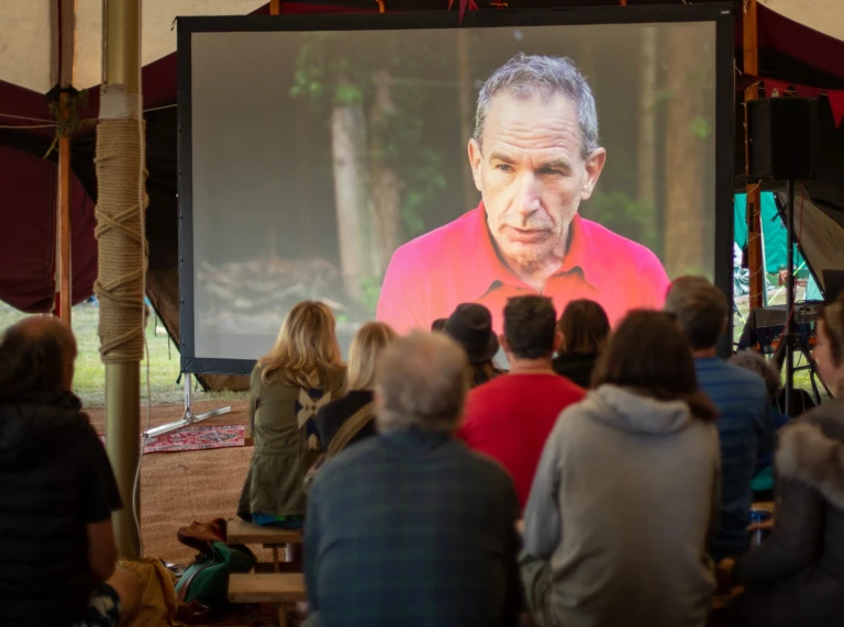 A group of people sat watching a film on a projector screen.
