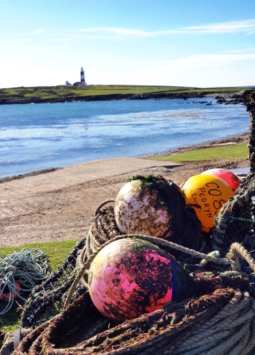 Rope and buoy's with the sea and a lighthouse in the background.