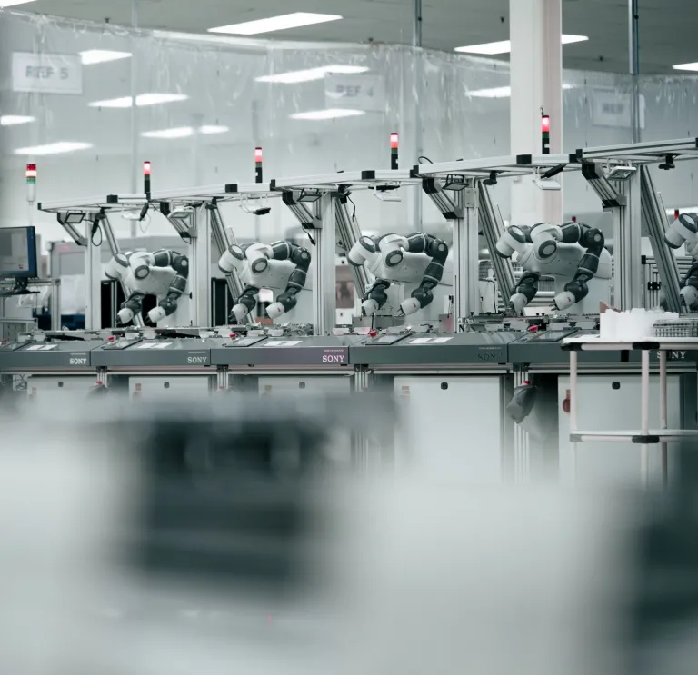 Robots alineados a lo largo de un banco de trabajo en un entorno técnico de fábrica impecable.