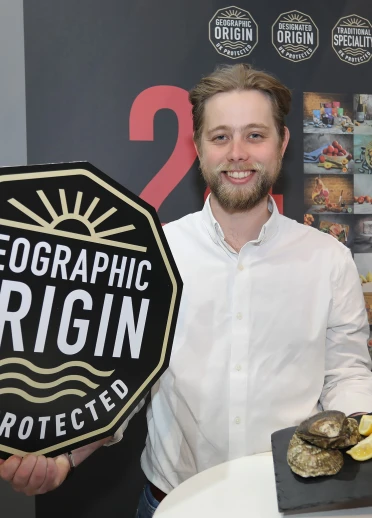 A man smiling at the camera holding a plate of oyters.