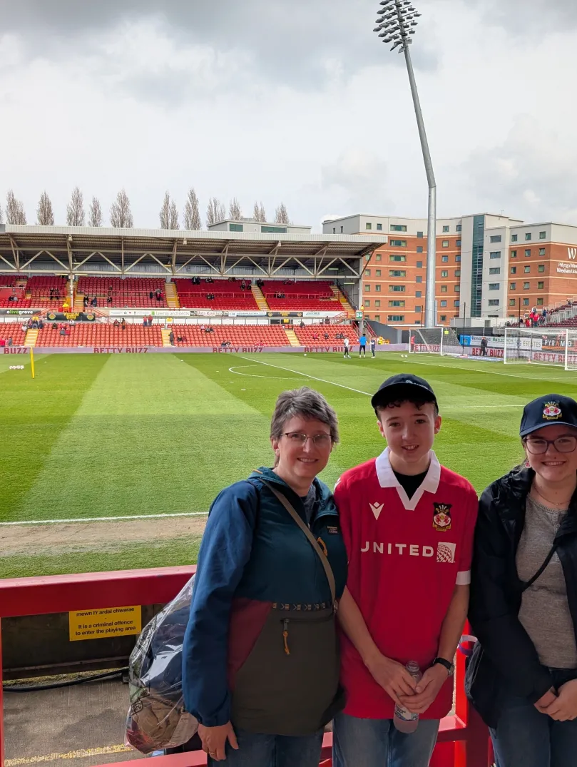 Four people wearing Welsh football shirts standing inside the stadium