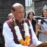 Raj stood in front of mic reading at an event in Wales