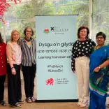 Women in front of Urdd poster