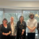 six people stood in front of window smiling