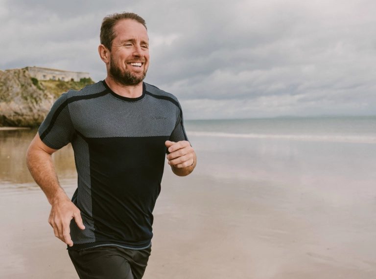 Shane Williams court le long de la Plage Nord de Tenby pendant l'entraînement pour le triathlon Ironman Wales.