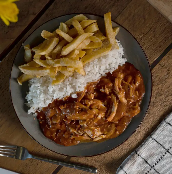 A plate of food with chips on the left, rice in the middle and curry on the right