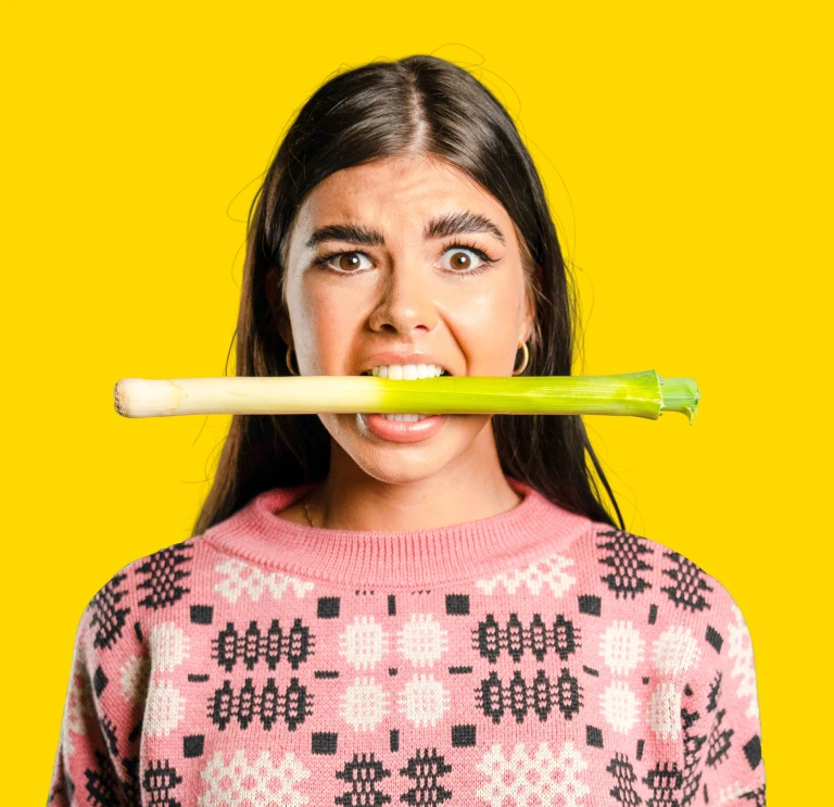 A girl holding a leek in her mouth
